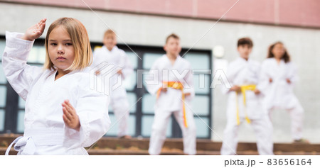Schoolgirl training karate at schoolyard with friends 83656164