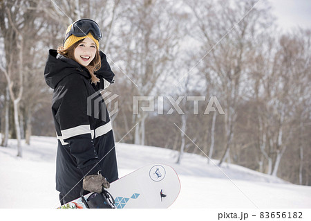 スノボを持ってカメラ目線で立つ若い女性　スノーボードイメージ　 83656182