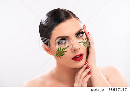Beautiful woman touching her healthy skin with two hands. Beautiful girl model with fresh glowing hydrated facial skin and makeup on isolated on white background. Close up shot 83657157