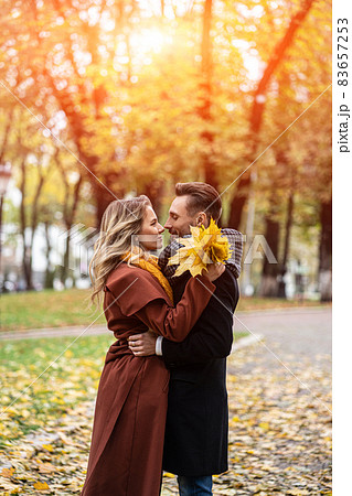 Husband and a wife hugged smile looking at each other in the autumn park. Half-length portrait of a kissing young couple. Outdoor shot of a young couple in love in a autumn park Husband and a wife hugged smile looking at each other in the autumn park. Half-length portrait of a kissing young couple. Outdoor shot of a young couple in love in a autumn park 83657253
