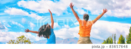 Happy people jumping of fun enjoying travel adventure. Young couple from behind happiness jump banner panorama in blue sky. Happy people jumping of fun enjoying travel adventure. Young couple from behind happiness jump banner panorama in blue sky. 83657648
