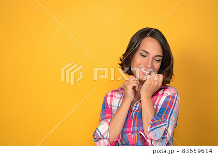 Charming woman expressing tenderness and saying good bye in plaid shirt on a yellow background with copy space. Facial expressions, emotions, feelings 83659614