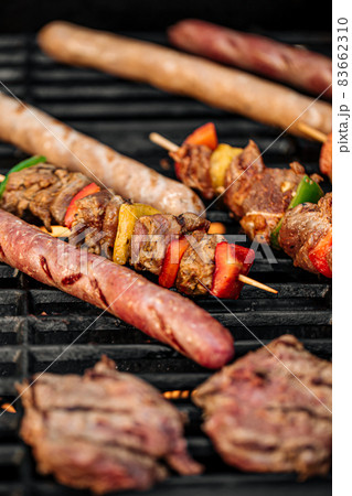 Grilling sausages and skewers on a barbecue Grilling sausages and skewers on a barbecue 83662310