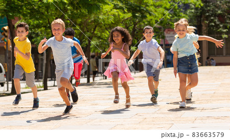 Group of joyful children running down the summer street Group of joyful children running down the summer street 83663579