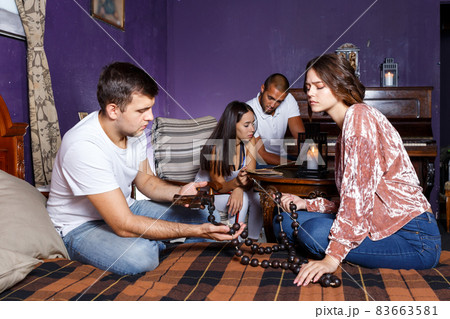 Friends looking at wooden rosary in quest room Friends looking at wooden rosary in quest room 83663581