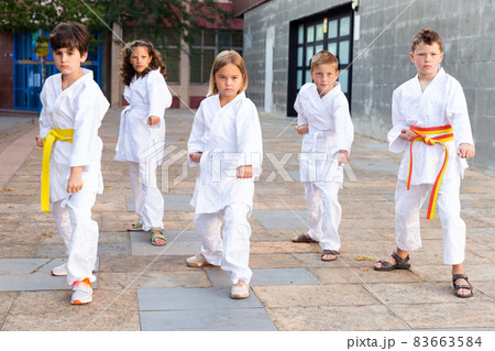 Tweenagers exercising karate moves in courtyard of sports school Tweenagers exercising karate moves in courtyard of sports school 83663584
