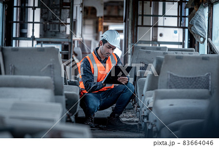 Engineer under discussion inspection and checking construction process railway switch and checking work on railroad station .Engineer wearing safety uniform and safety helmet in work. 83664046