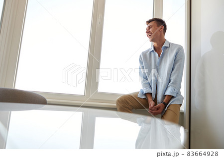 Happy beautiful handsome smiling caucasian man is relaxing at modern light home Happy beautiful handsome smiling caucasian man is relaxing at modern light home 83664928
