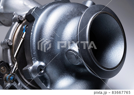 Auto parts new mechanical turbine made of metal on a gray background. Close-up. Mechanical Turbo Exhaust Compressor Auto parts new mechanical turbine made of metal on a gray background. Close-up. Mechanical Turbo Exhaust Compressor 83667765