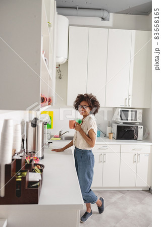 Pretty young employer having break in coworking kitchen 83668165