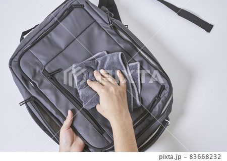 Cleaning backpack with washcloth. A person wipes off dirt or dust from the outside of the bag. Wiping school bag with damp cloth 83668232