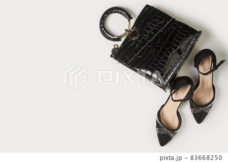 Black leather womens shoes and trendy handbag on white background. Womens accessories. Top view. Black leather womens shoes and trendy handbag on white background. Womens accessories. Top view. 83668250