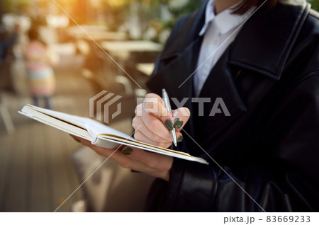 Close-up of unrecognizable young business woman holding a pen and notepad, writing, making notes. Close-up of unrecognizable young business woman holding a pen and notepad, writing, making notes. 83669233