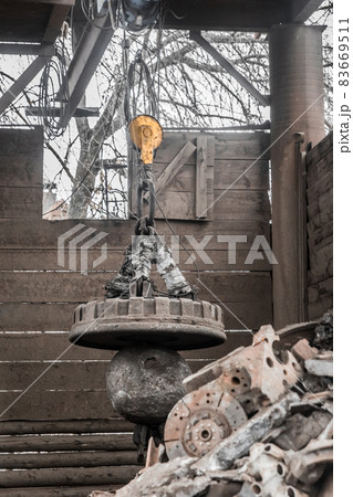 Magnetic scrap crane recycles and unloads junk and old metal in a landfill Magnetic scrap crane recycles and unloads junk and old metal in a landfill 83669511