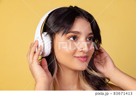 Close-up portrait of young beuatiful girl, student listening to music isolated on yellow studio backgroud. Close-up portrait of young beuatiful girl, student listening to music isolated on yellow studio backgroud. 83671413