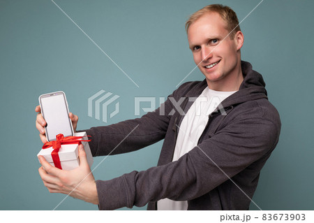 Handsome happy young blonde male person isolated over blue background wall wearing casual stylish Handsome happy young blonde male person isolated over blue background wall wearing casual stylish 83673903