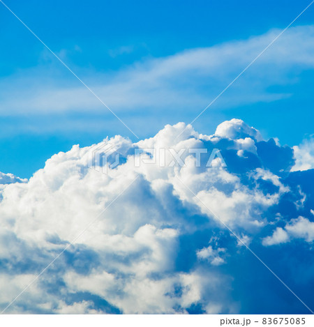 White fluffy cumulus clouds on the clear blue sky in the sunshine. Top view from the plane. Background for design. Square photo 83675085