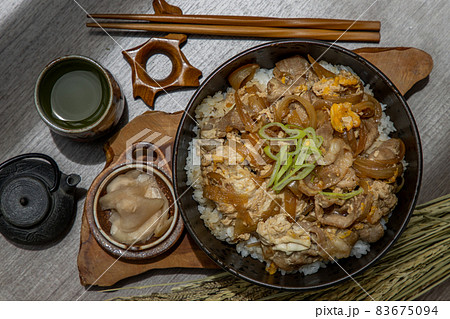 Japanese pork rice bowl with egg and onion (Donburi) served with pickled ginger and green tea. Japanese pork rice bowl with egg and onion (Donburi) served with pickled ginger and green tea. 83675094