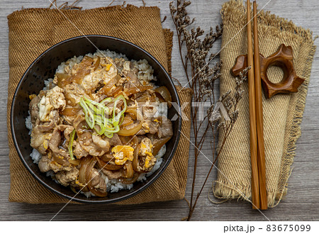 Japanese pork rice bowl with egg and onion (Donburi) served with pickled ginger and green tea. Japanese pork rice bowl with egg and onion (Donburi) served with pickled ginger and green tea. 83675099