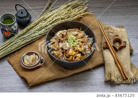 Japanese pork rice bowl with egg and onion (Donburi) served with pickled ginger and green tea. Japanese pork rice bowl with egg and onion (Donburi) served with pickled ginger and green tea. 83675120
