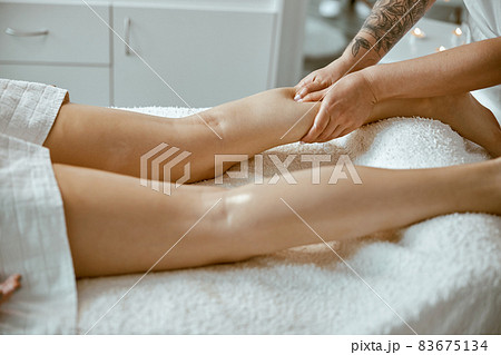 Professional caucasian specialist is doing leg message at modern minimalistic salon 83675134
