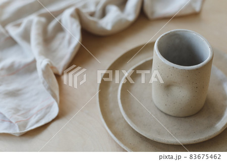 Beige ceramic plate on a wooden table top view. minimalist handmade ceramic tableware and pottery. Beige ceramic plate on a wooden table top view. minimalist handmade ceramic tableware and pottery. 83675462