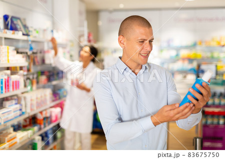 Male customer looking for products of body care in pharmacy closeup 83675750