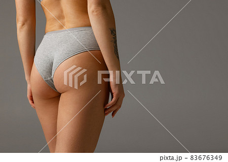 Back view of sportive body, bottocks of young woman in grey bottocks isolated on gray studio background. Natural beauty concept Back view of sportive body, bottocks of young woman in grey bottocks isolated on gray studio background. Natural beauty concept 83676349