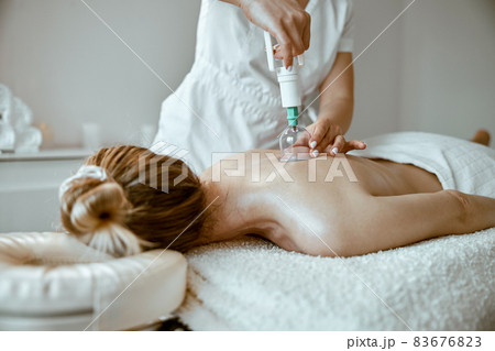 professional female specialist is doing cupping therapy on the back of beautiful caucasian lady professional female specialist is doing cupping therapy on the back of beautiful caucasian lady 83676823