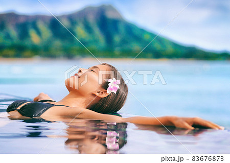 Hawaii vacation luxury resort travel Asian tourist girl relaxing in hotel infinity pool by Waikiki beach in Honolulu, Oahu. USA travel. Hawaii vacation luxury resort travel Asian tourist girl relaxing in hotel infinity pool by Waikiki beach in Honolulu, Oahu. USA travel. 83676873
