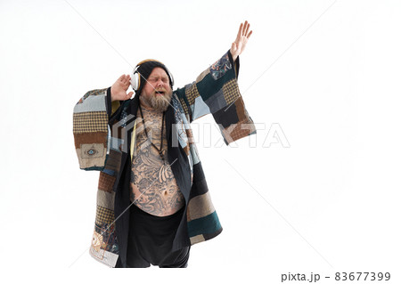 Fat stylish bearded tattoed caucasian man with big belly is posing and dancing wearing ethnic kimono Fat stylish bearded tattoed caucasian man with big belly is posing and dancing wearing ethnic kimono 83677399