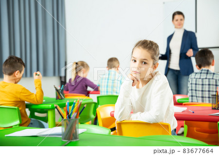 Portrait of tired schoolgirl sitting in classroom elementary school 83677664