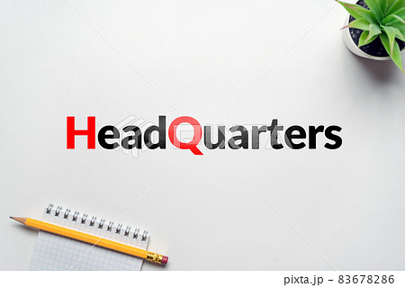 Business acronym HQ or Headquarters. On the table a flower and a notebook with a pencil 83678286