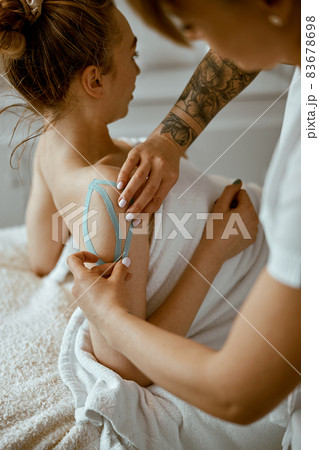 Confident female doctor is doing taping procedure in modenr treatment cabinet Confident female doctor is doing taping procedure in modenr treatment cabinet 83678698