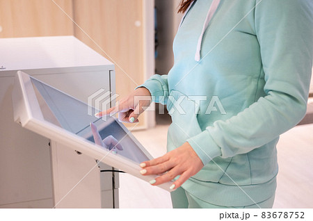 Faceless woman touching the screen of a self-service device in a store. Device store navigator. Self purchase. 83678752