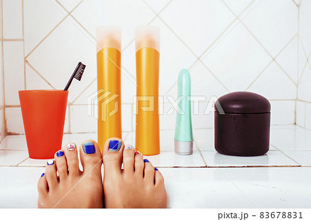 woman legs in bathroom with lot of stylish stuff for care, pedicure creative design, hygiene spa mani pedi concept woman legs in bathroom with lot of stylish stuff for care, pedicure creative design, hygiene spa mani pedi concept 83678831