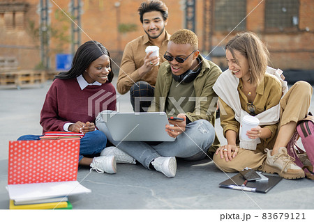 Students watching something on laptop on asphalt Students watching something on laptop on asphalt 83679121