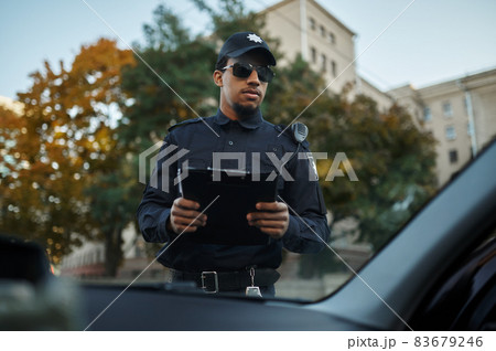 Male police officer in sunglasses holds notebook Male police officer in sunglasses holds notebook 83679246