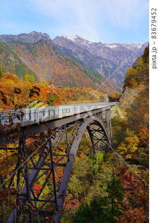 紅葉した奥飛騨温泉郷の北アルプス大橋と冠雪した笠ヶ岳の写真素材