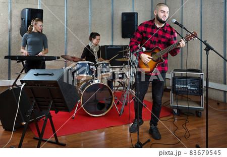 Bearded guy soloist playing guitar in studio 83679545