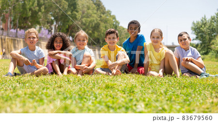 Group of happy kids friends resting on grass together in park Group of happy kids friends resting on grass together in park 83679560