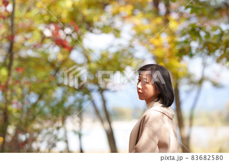 秋の公園で寂し気な中年女性　 83682580