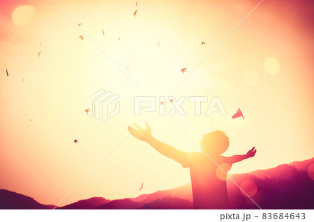 Freedom feel good and travel adventure concept. Copy space of silhouette man rising hands on sunset sky double exposure colorful bokeh and bird fly background. 83684643