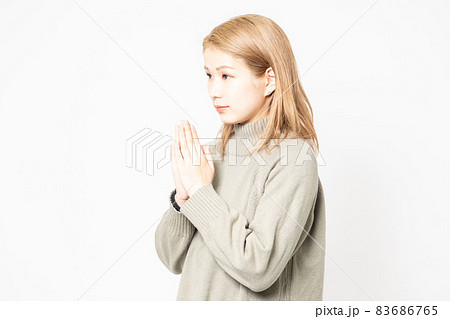 掌を合わせてお願いするセーターを着た若い女性 83686765