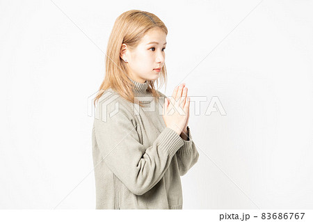 掌を合わせてお願いするセーターを着た若い女性 掌を合わせてお願いするセーターを着た若い女性 83686767