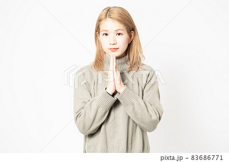 掌を合わせてお願いするセーターを着た若い女性 83686771
