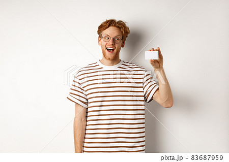 Shopping and finance concept. Amazed caucasian redhead man showing plastic card, saying wow and staring impressed at camera, white background 83687959