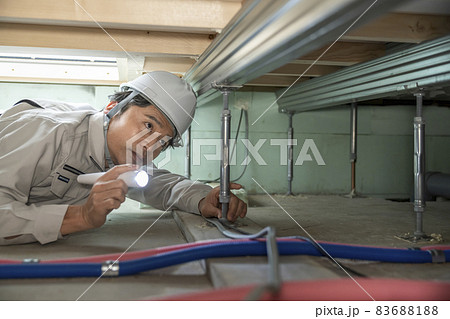 住宅の床下を点検する作業服の男性 83688188