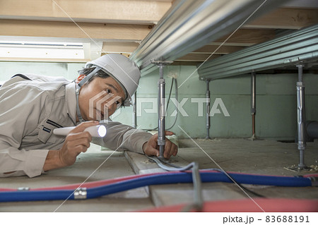 住宅の床下を点検する作業服の男性 83688191