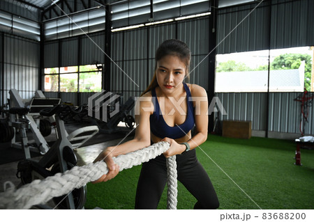 Attractive sportswoman doing exercise with battle ropes. 83688200